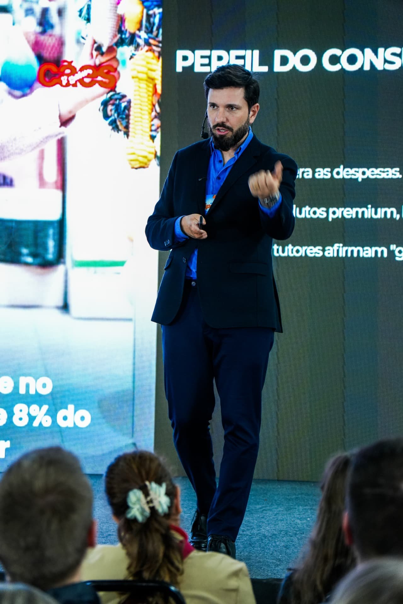 Alexandre Welsbacher palestrando com microfone headset diante do público