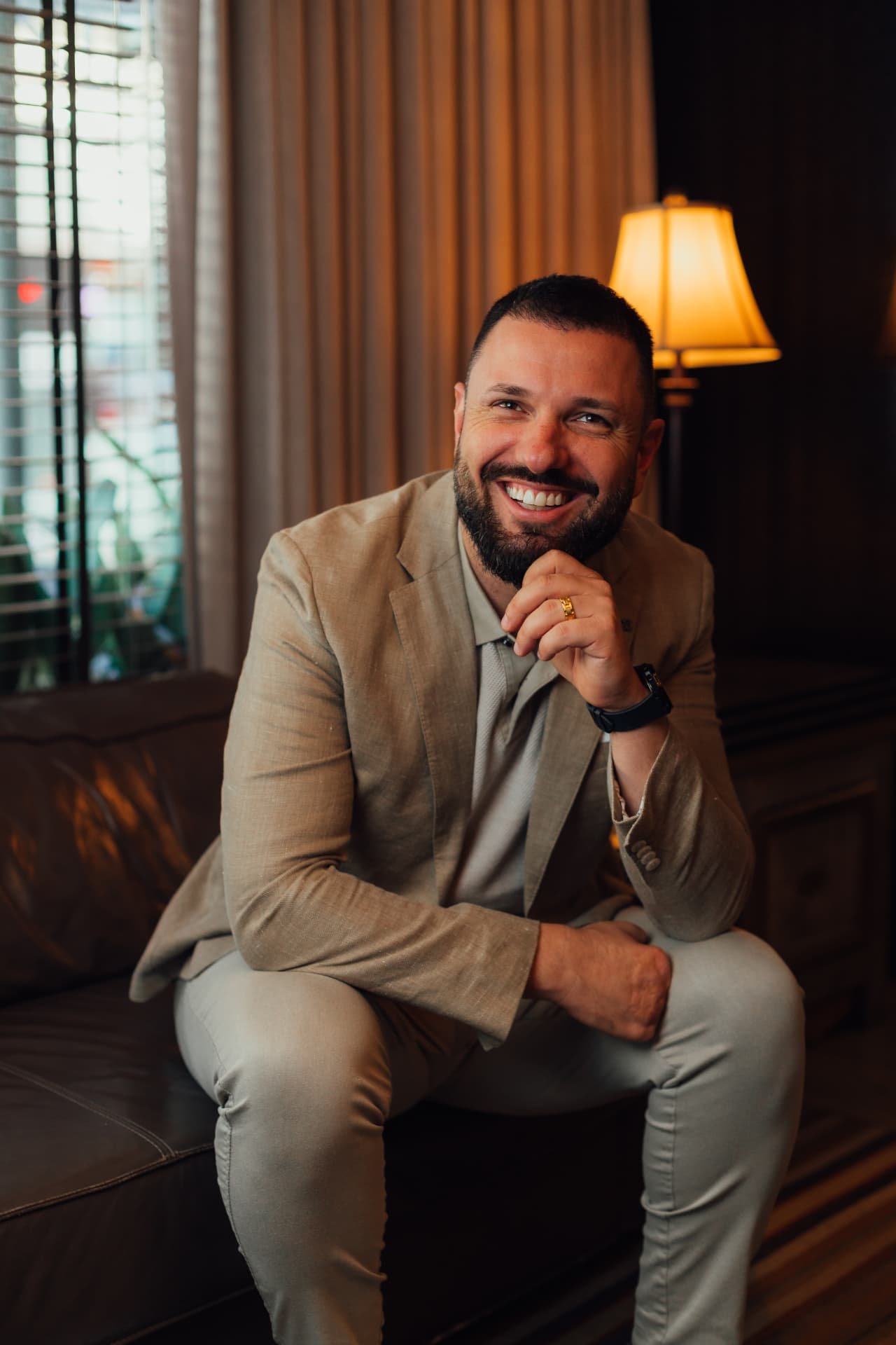 Alexandre Welsbacher sentado, sorrindo, em ambiente corporativo